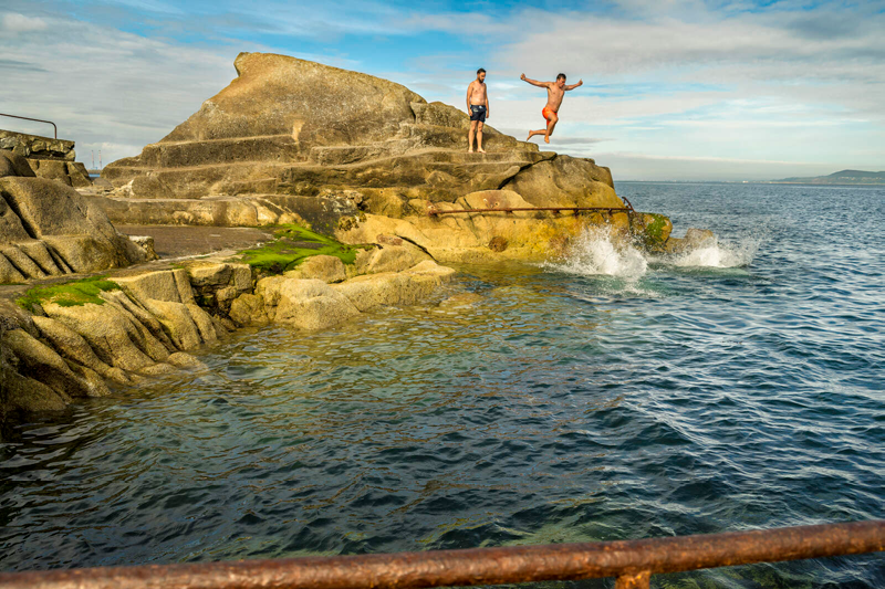 Two men jumping off The Forty Foot