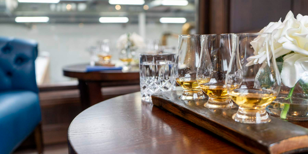 Tasting glasses of whiskey presented on a wooden tasting board