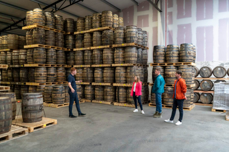 A photograph of a tour of Powerscourt distillery in which barrels are stacked in their warehouse.