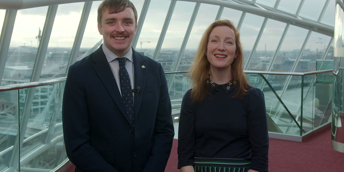 Close-up of a man and a woman standing in front of a window while smiling at the camera