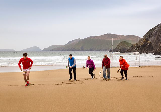 Five delegates take part in a hurling lesson on the beach