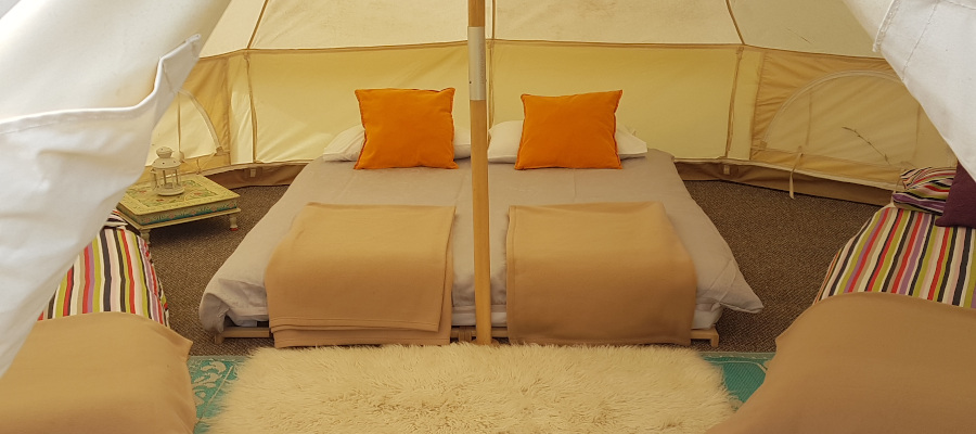 Bell tent interior with futon and cushions