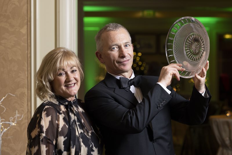 Professor Liam Glynn in a tuxedo holding an award plate, standing next to a smiling woman, both dressed formally at the Conference Ambassador Recognition Awards.