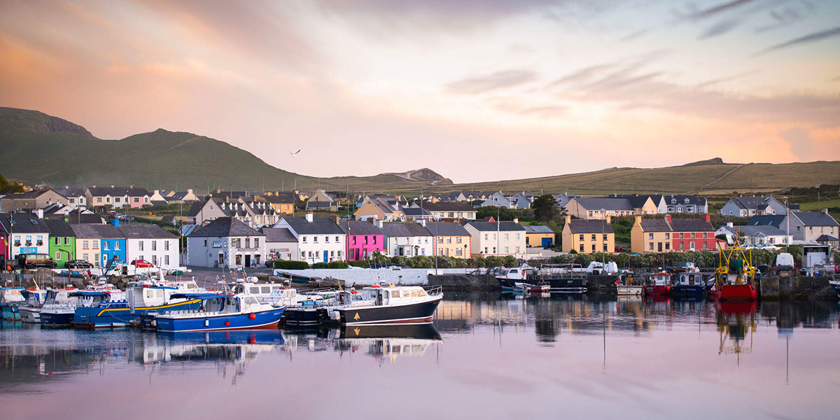 A scenic view of colourful houses and boats docked at a quiet harbour in Portmagee