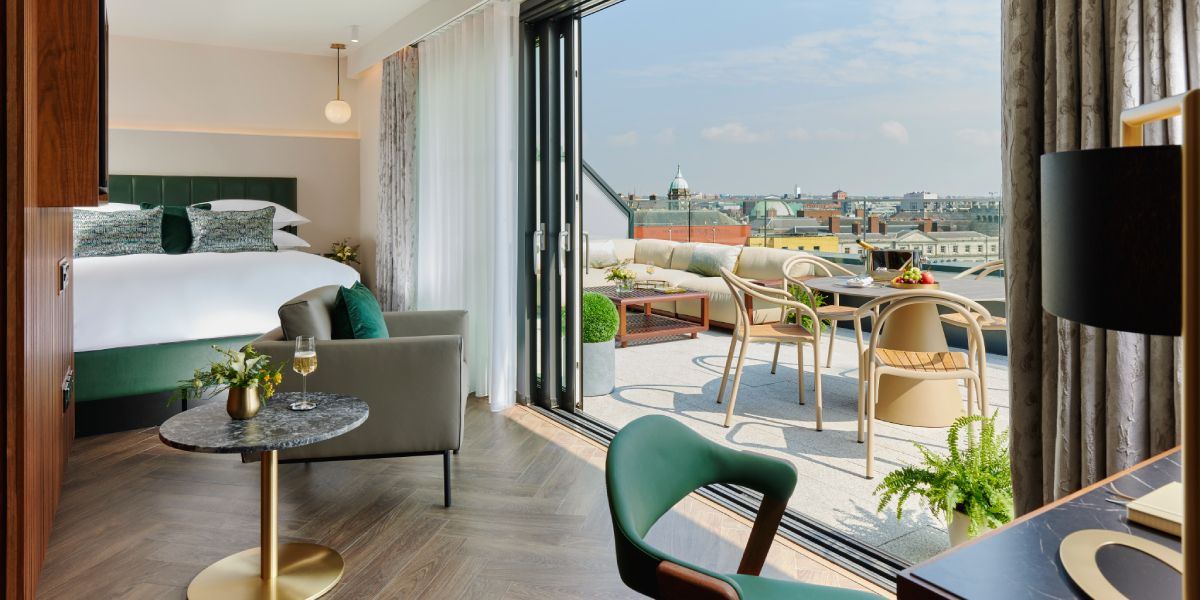 Modern hotel room with a private terrace offering stunning city views, perfect for business events.
