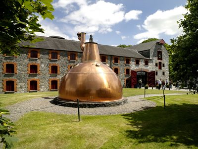 Old copper pot still at Middleton Distillery, with building in background
