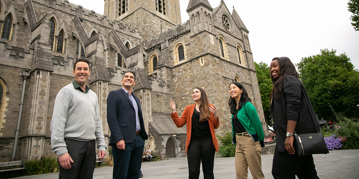 Group of people standing in front of a cathedral having a chat.