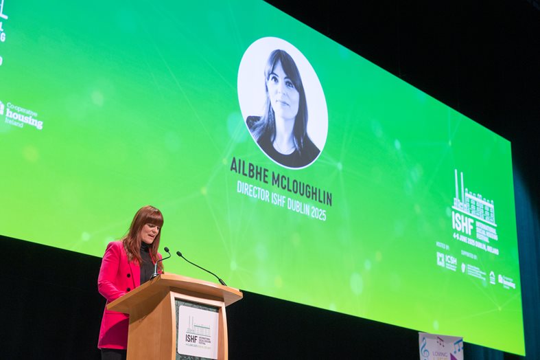 A woman standing at a podium talking on stage at the ISHF conference in Dublin