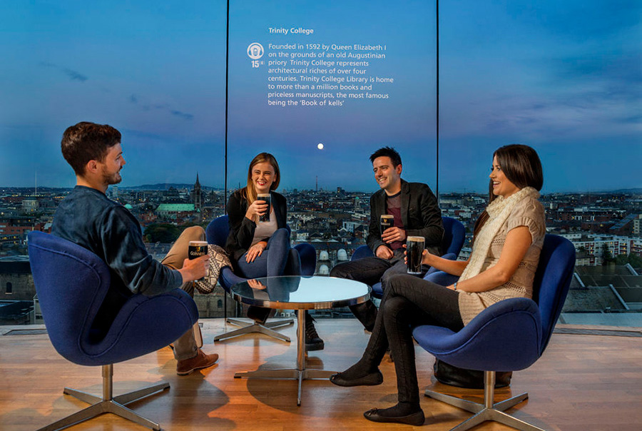 Four delegates drink Guinness while sat in front of the floor-to-ceiling windows in the Gravity Bar
