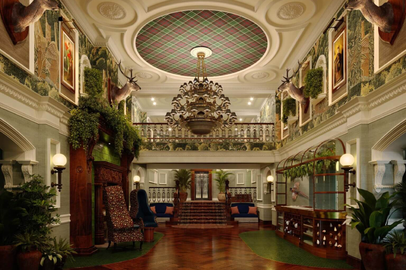 An opulent entrance hall with a grand chandelier, rich wood panelling and stag heads mounted on the walls
