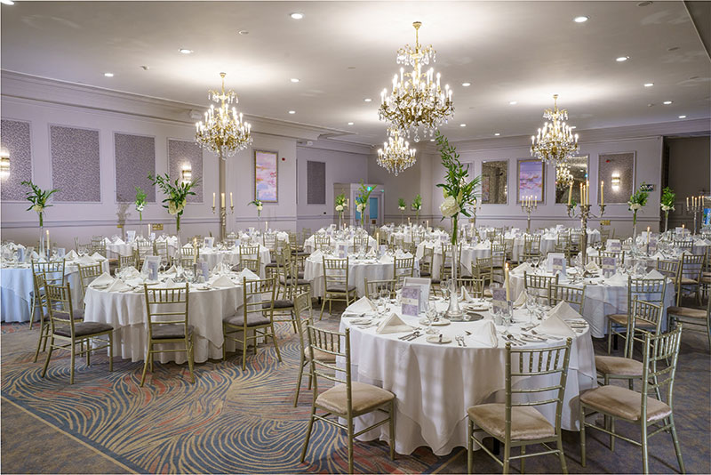 Elegant dining room set up with round tables, white linens and chandeliers