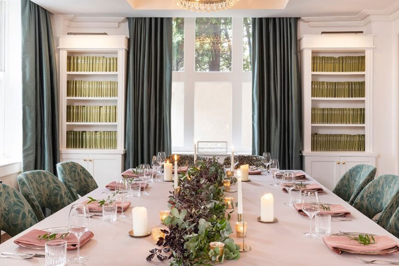 A bright private dining room with an elegant table and green velvet chairs