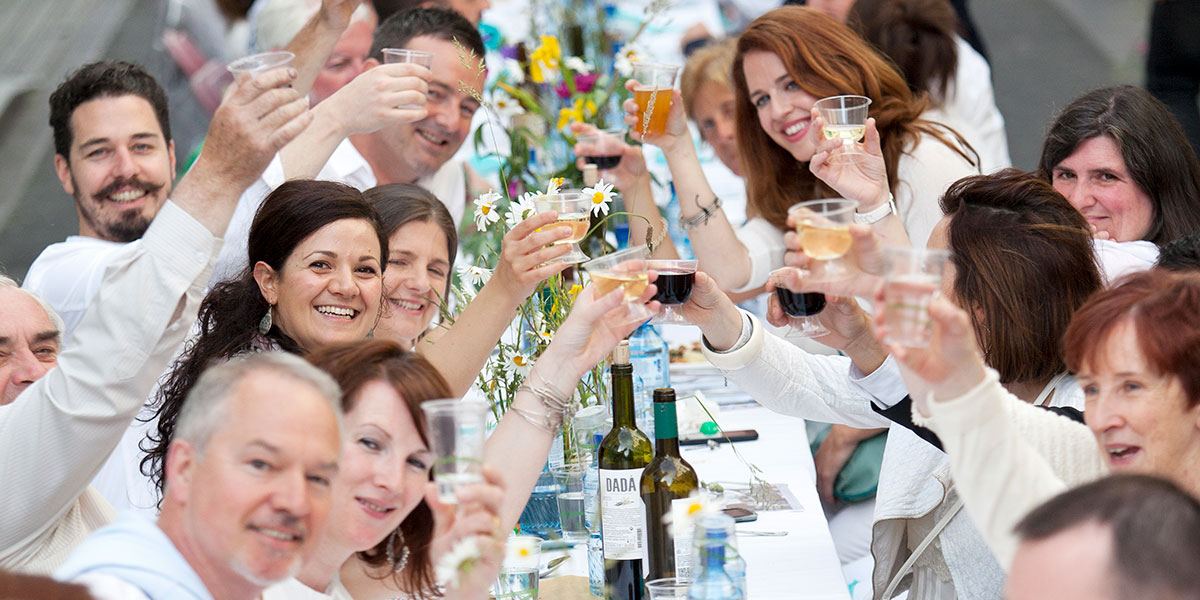 A group of people sitting at a table and raising a toast